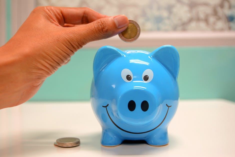hand placing coins into a piggy bank