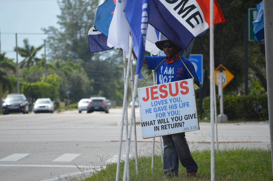 man holding up a sign by the road